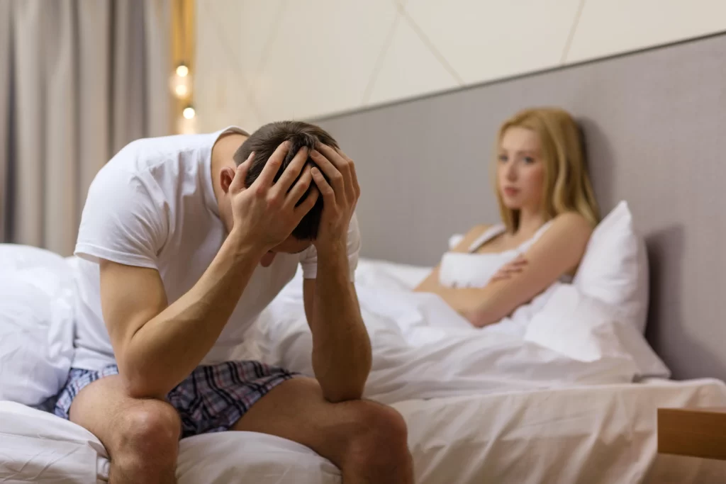 A man sitting on the bed with his head in his hands.