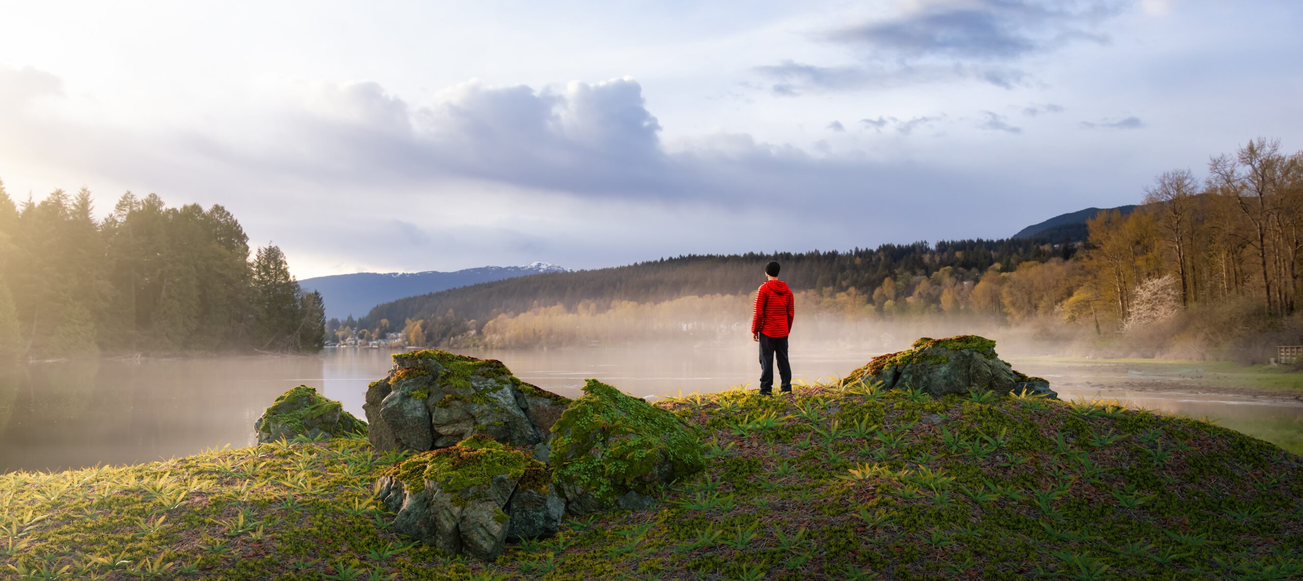 A person standing on top of a hill near some rocks.