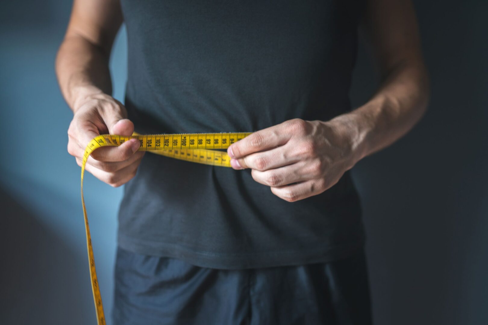 A person is measuring their waist with a tape measure.