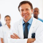 A man in white lab coat standing next to other people.